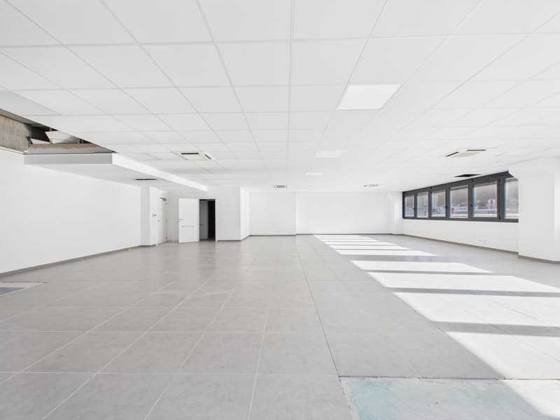 Empty room with white walls, tiled floor, and large windows