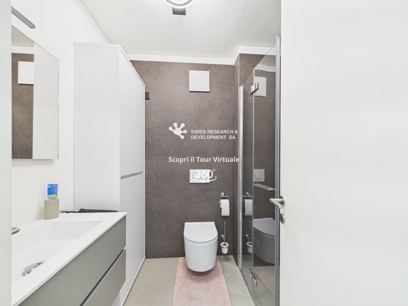 modern bathroom with white sink, white toilet, grey walls, mirror, and glass shower