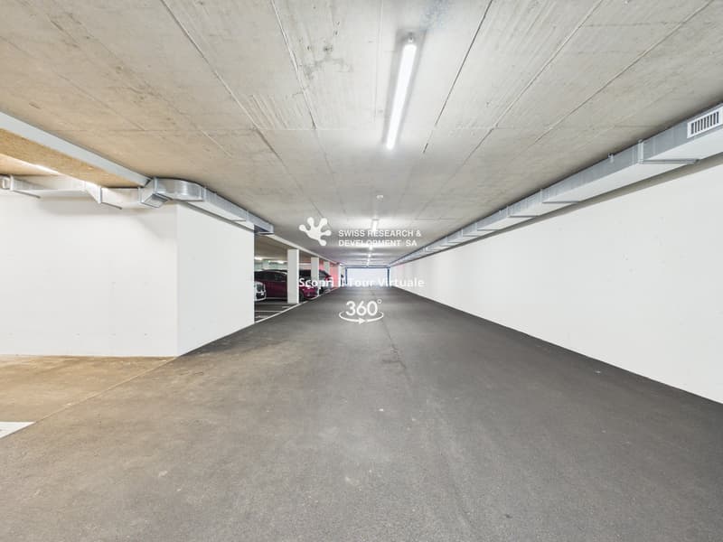 Empty parking lot with white walls, grey floor, and ceiling lights