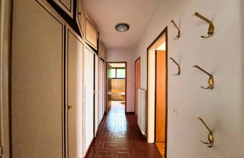 tiled floor, white walls, wooden doors, radiator, hallway leading to rooms