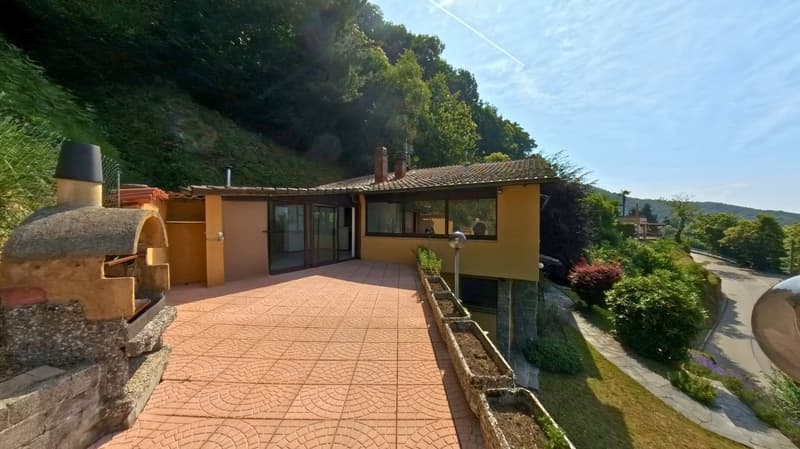 yellow house, brick walkway, outdoor fireplace, large windows, trees, mountain view