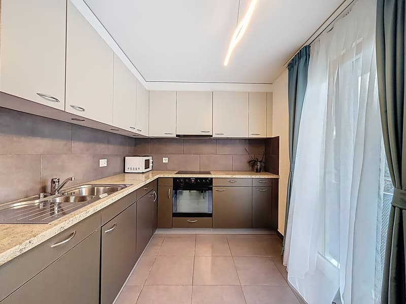 modern kitchen with white cabinets, granite countertops, stainless steel sink, built-in microwave, oven, dishwasher, and a faucet