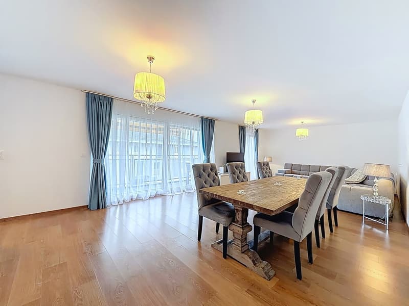 Dining room with wooden floor, large windows, chandeliers, dining table, chairs, couch, side table, lamp