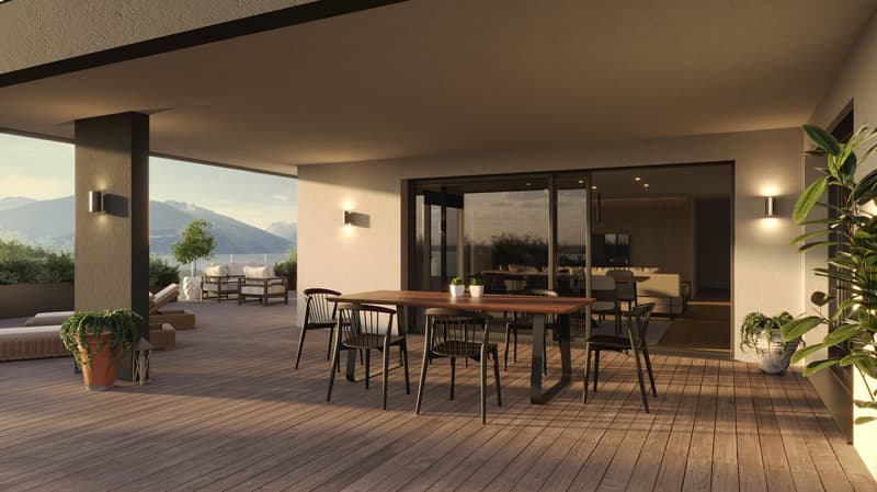 The image shows a spacious outdoor dining area with a large wooden table and chairs. The area has a covered patio with large windows overlooking a scenic mountain landscape. There are potted plants and other decor elements that create a cozy and inviting