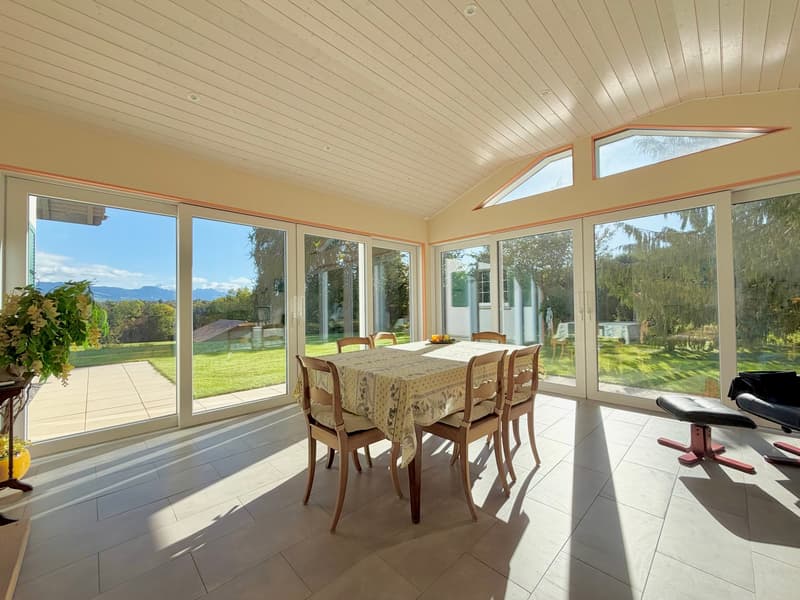 Modern dining room with wooden table and chairs, panoramic windows, tiled floor, modern decor, outdoor patio, garden view