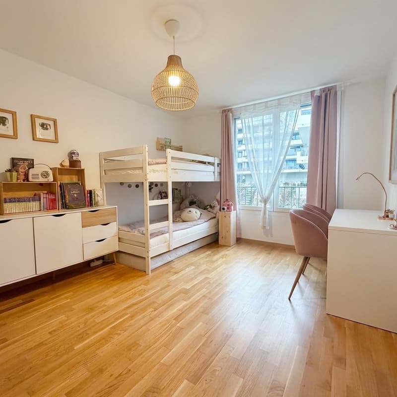 child's bedroom with wooden floor, bunk beds, white furniture, pink desk chairs, window with curtains, light fixture
