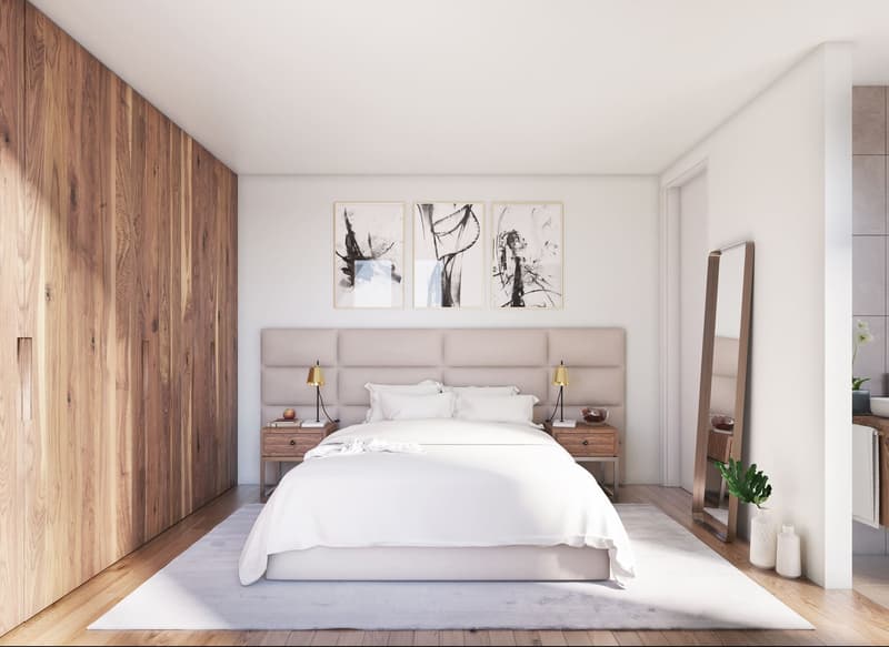 Minimalist bedroom with a double bed, wooden bedside tables, beige headboard, white walls, wooden flooring, and framed art pieces