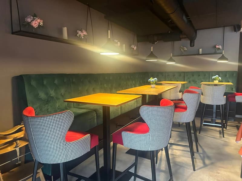 A restaurant with high ceilings, tables, chairs, and decor including flowers and lights