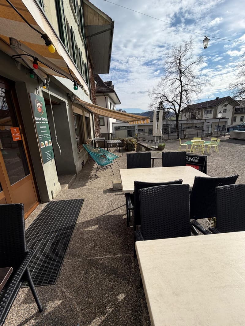 Outdoor seating area with tables and chairs, awning, and decorative lights