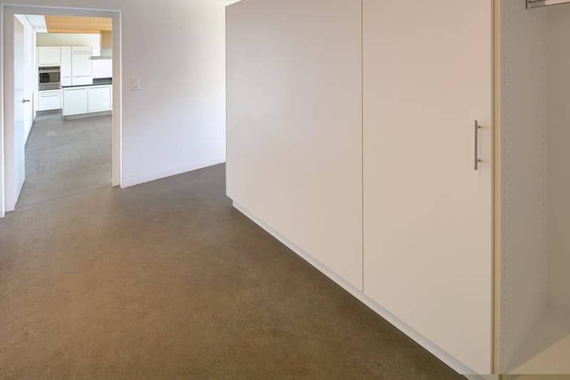 Open area, gray flooring, white walls, tall white cabinets