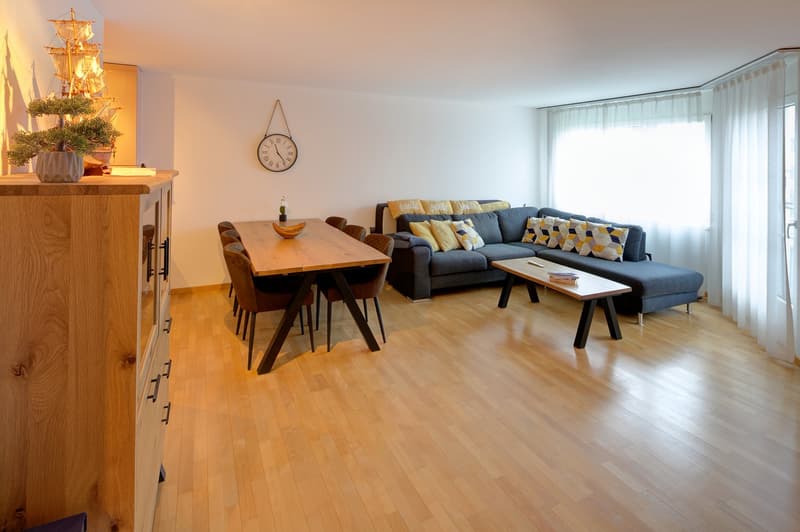 light hardwood floor, couch, dining table, wooden table, window, clock, plant