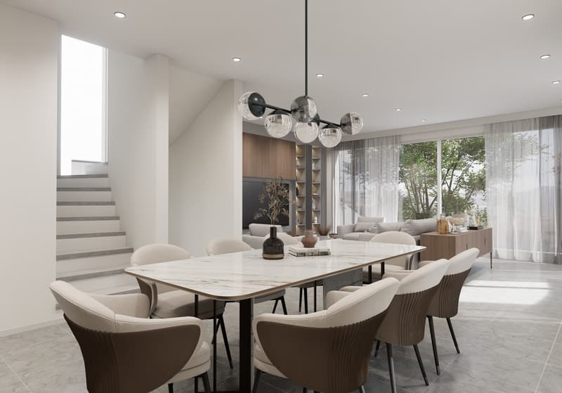 Spacious dining area with a large marble-top dining table, comfortable upholstered chairs, and a modern chandelier. The room features floor-to-ceiling windows providing a view of the outdoor greenery. There is also a built-in shelving unit along the wall.
