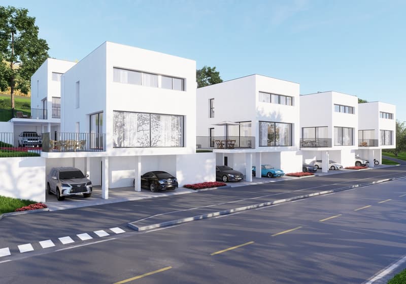 A modern residential complex with multiple white, minimalist-style townhouses or apartments. Each unit has a garage and designated parking spaces in the front. The buildings have large windows and balconies, and the complex is surrounded by greenery and l