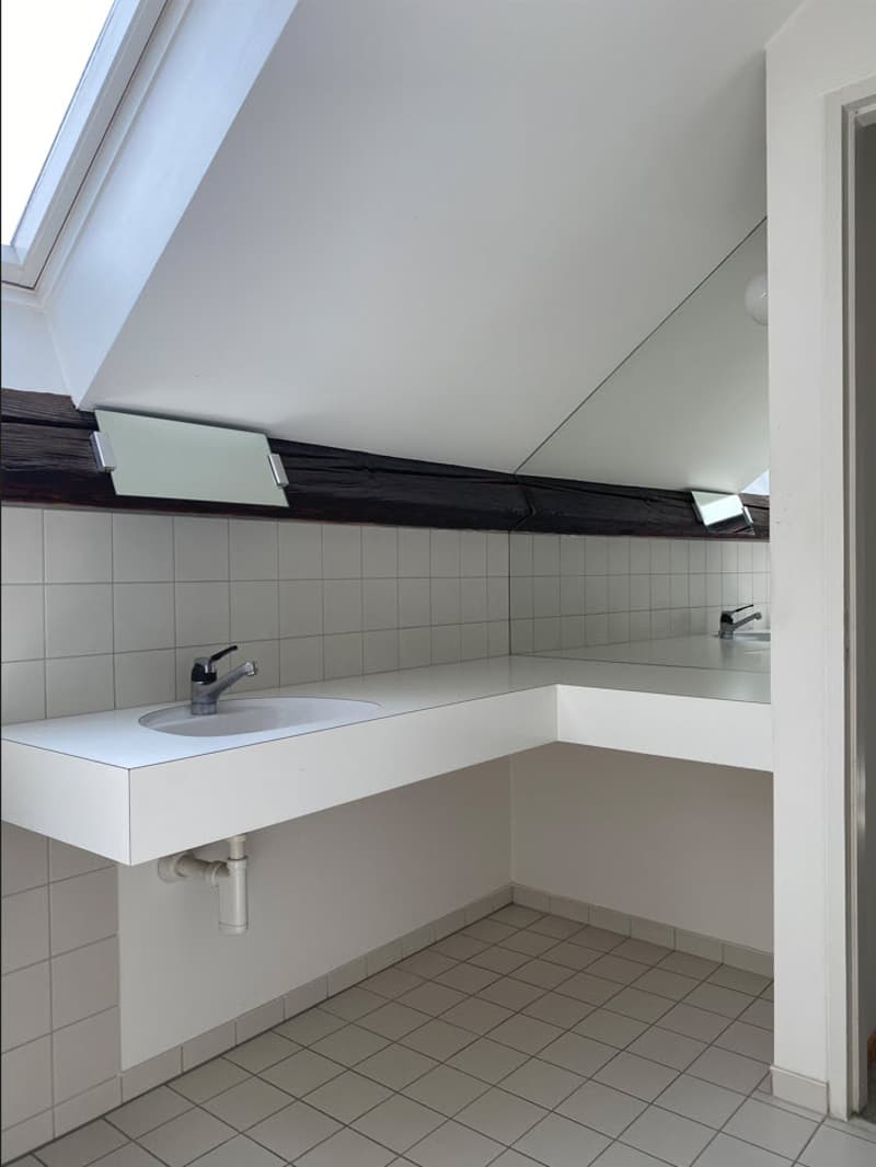 Bathroom with white sink, tiled walls and floor, and recessed lighting above the sink area