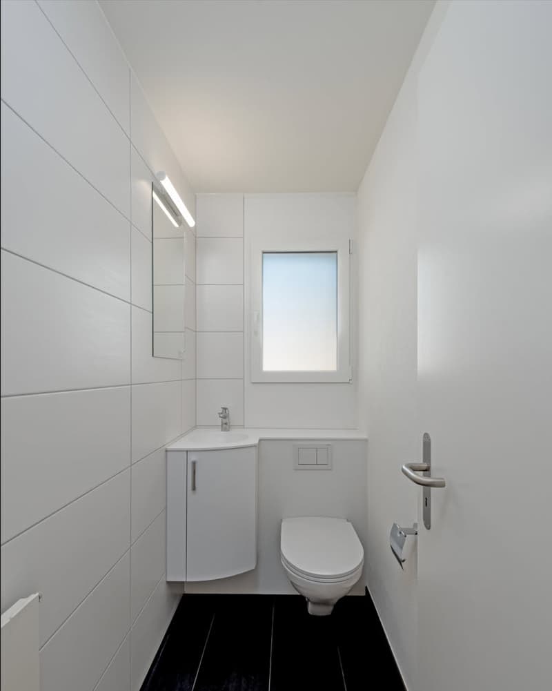 minimalist design, white tiles, dark floor, toilet, sink, mirror, small window
