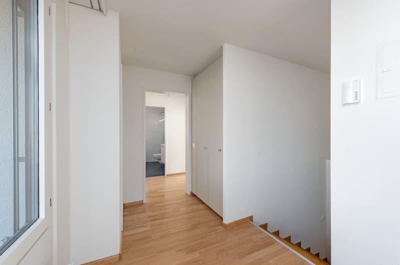 Empty hallway with hardwood floors and white walls.