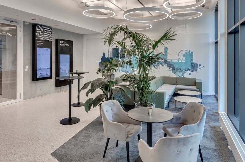 modern office reception area with round tables, chairs, plants, and a couch