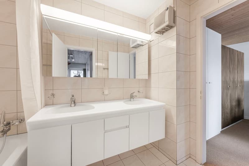 large vanity with two sinks, mirror, light over vanity, bathtub, tiled walls