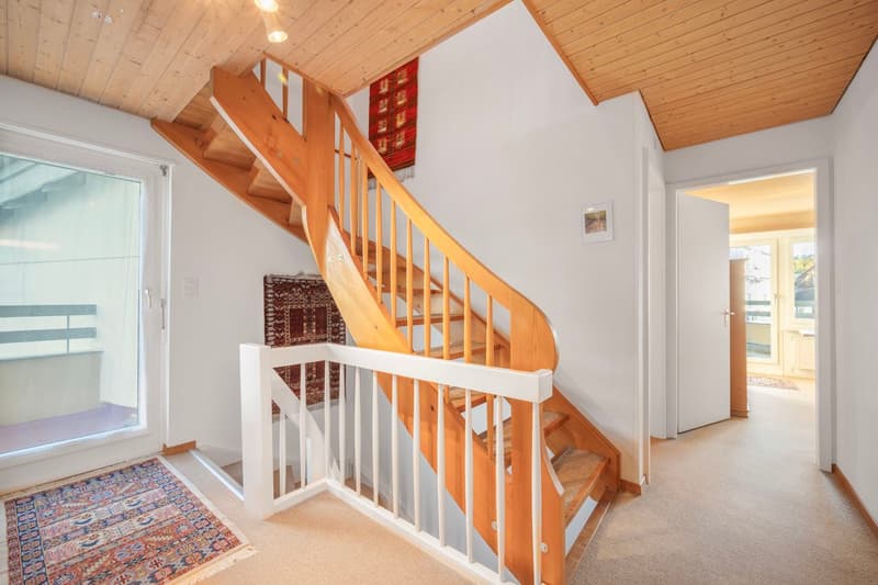 Entrance hall with wooden spiral staircase and carpet, glass door leading to balcony