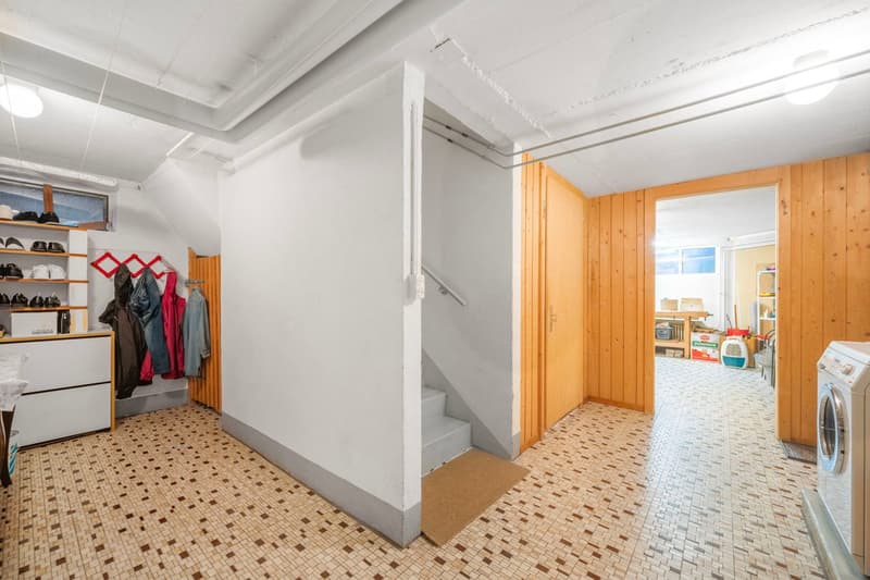 tiled floor, shelves with shoes, coats on hangers, washing machine, small staircase, wooden doors