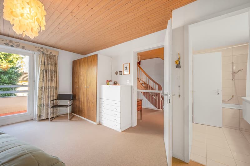 bright room with white walls, ceiling with wooden beams, balcony, white dresser, modern lighting, sliding glass door
