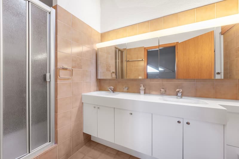 white bathroom vanity, double sinks, mirror, shower enclosure, tiled walls, tiled floor