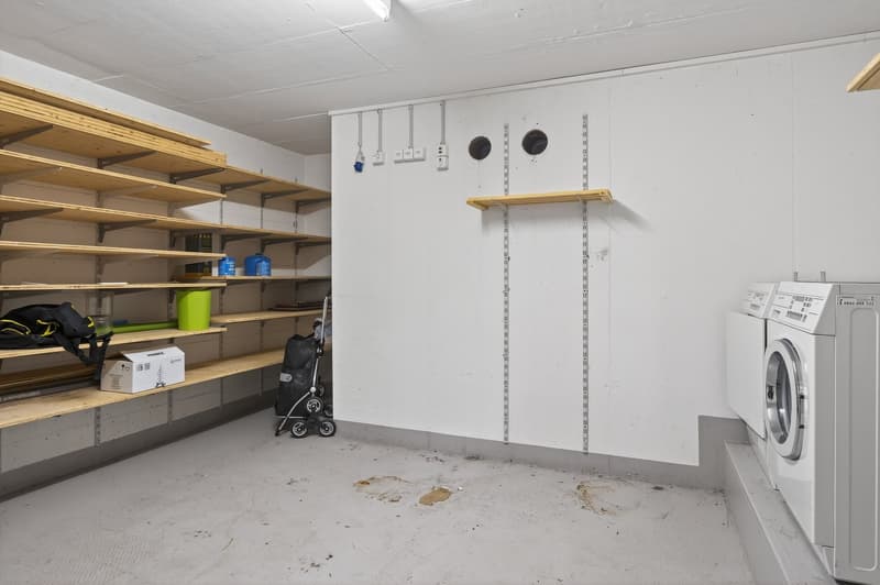 Laundry room with shelves, washing machines, boxes, and a stroller.