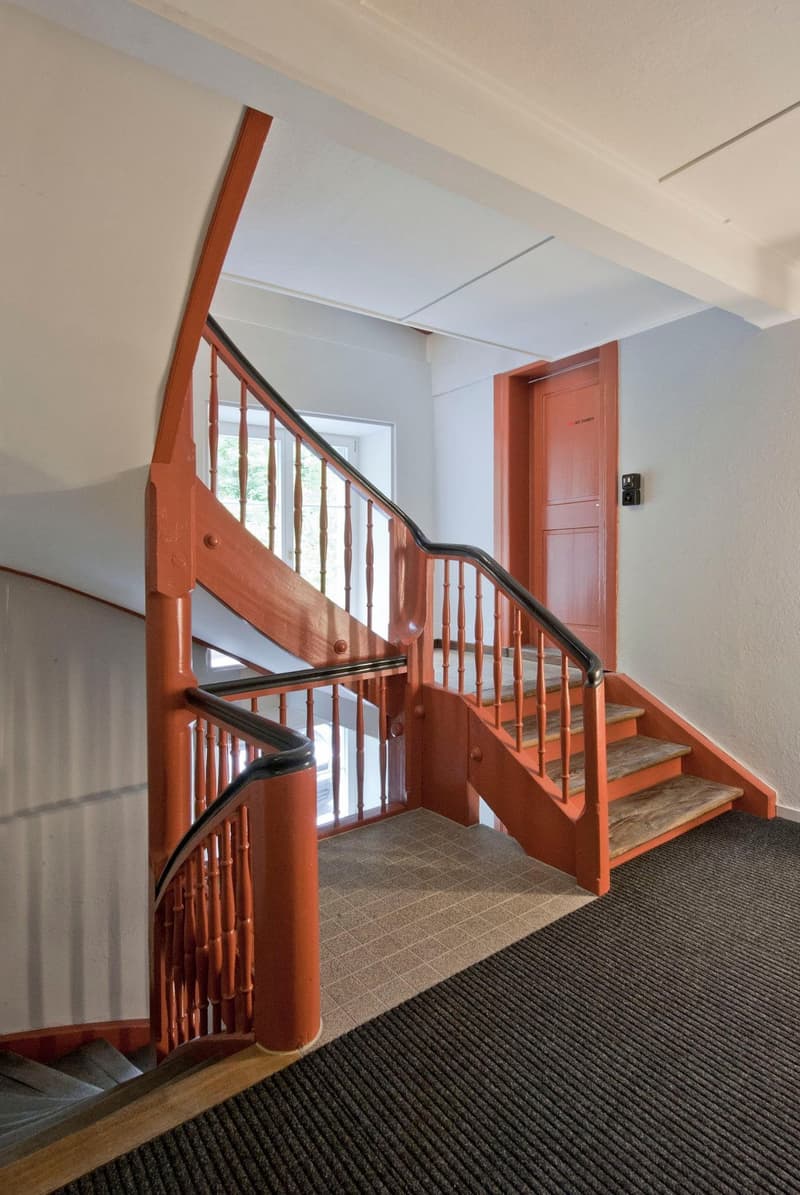 wooden staircase, red painted, black handrail, carpeted floor