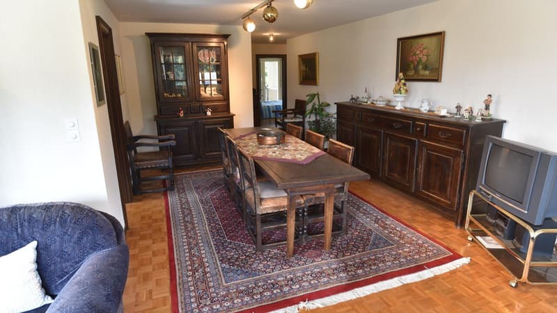 Large dining room with wooden furniture, including a dining table with chairs, a hutch, and a sideboard. The room also features a fireplace, hardwood floors, and a Persian-style rug.