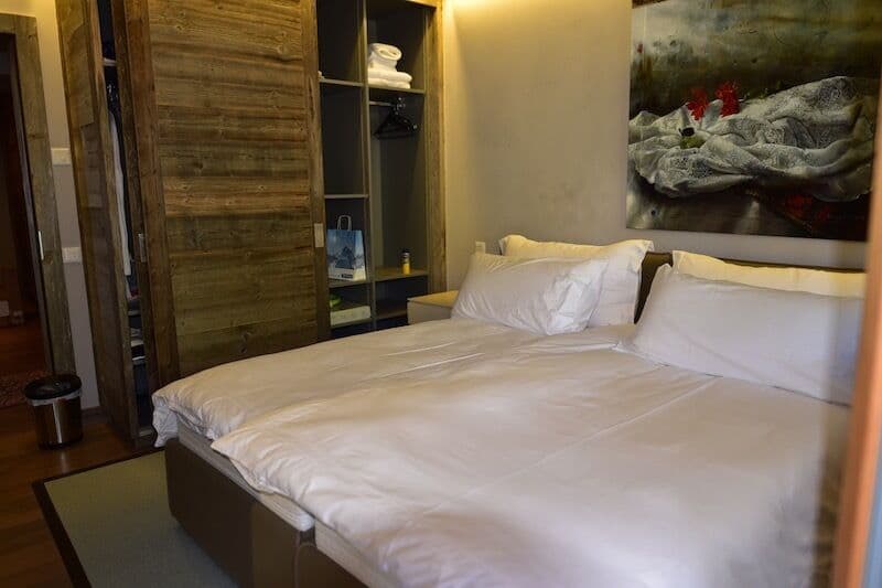 Rustic wooden walls, large bed with white bedding, wardrobe, artwork on the wall
