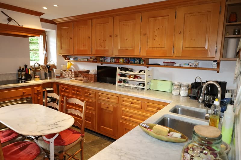 Spacious kitchen with wooden cabinets, marble countertops, a dishwasher, a private washing machine, and various kitchen appliances and utensils. The kitchen also has a dining table with chairs.