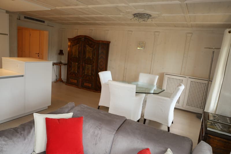 white kitchen, gray couch, table with glass top, 4 white chairs, radiator, dark wooden cabinet