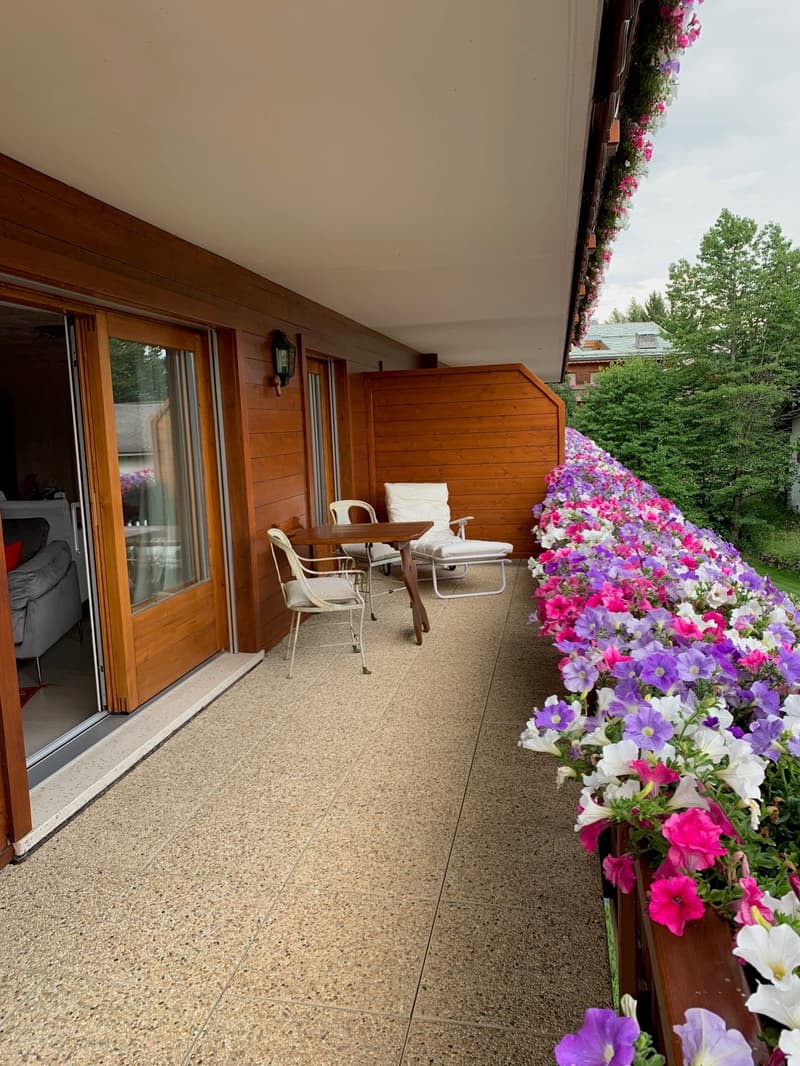 balcony with wooden railing, patio furniture, flower plants, view of surroundings