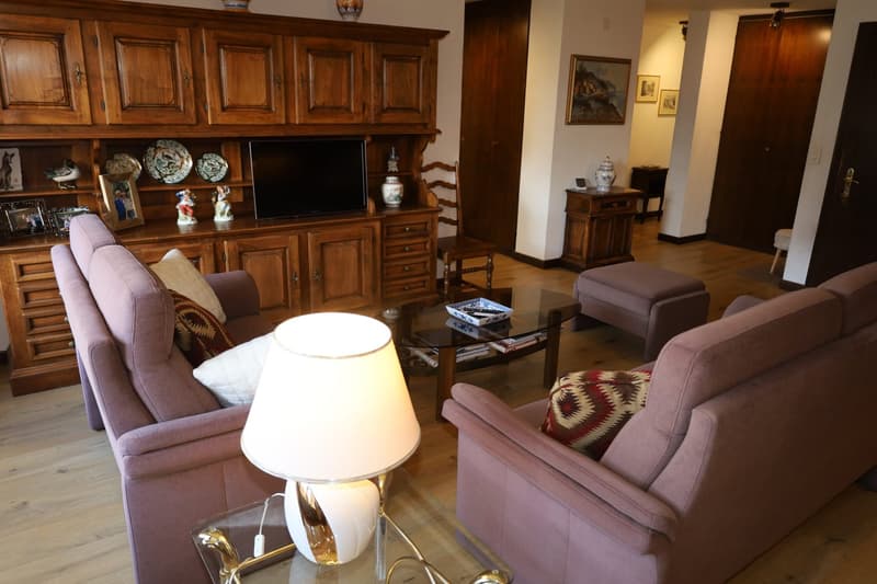 wooden cabinet, flat screen TV, decorative items, two couches, coffee table, wooden chair, lamp