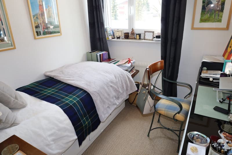 a single bed, a chair, desk, carpet, bed covered in white and blue plaid blanket