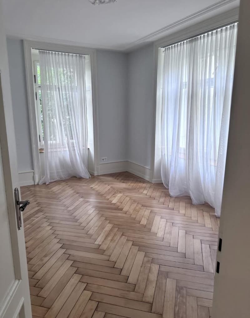 empty room, wooden parquet flooring, white walls, white curtains, two windows