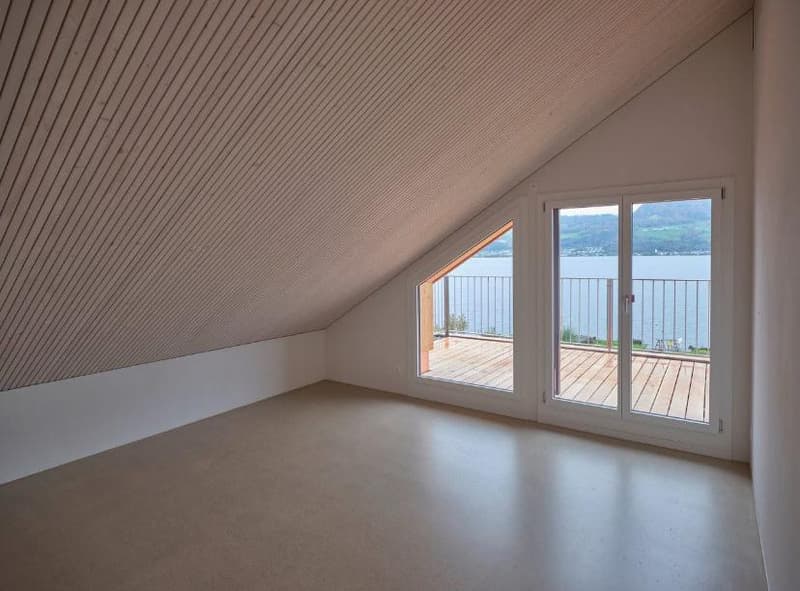 empty attic room, wooden ceiling, large glass doors, wooden balcony, lake view