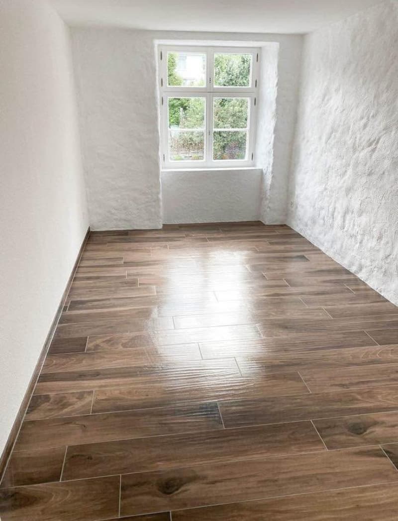 white walls, wooden tiles floor, large window, no furniture