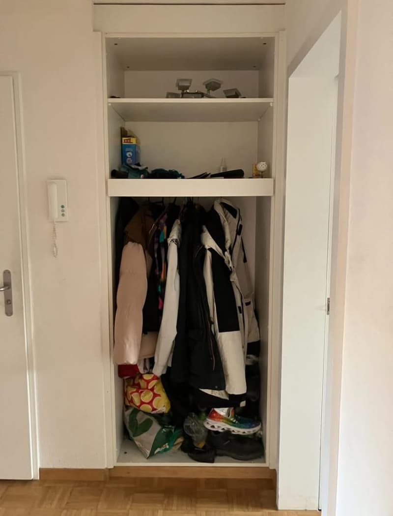 closet with shelves, fully stocked with jackets and shoes, open door