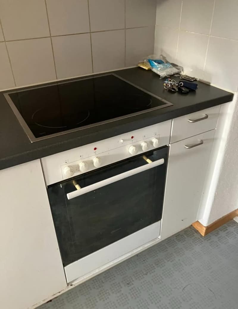 white oven, induction hob, tile wall, white kitchen units, grey floor