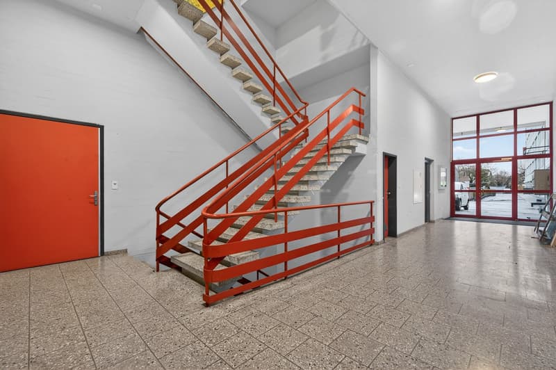 Ground floor of a two story building, tiled floor, staircase with red handrails, orange entrance door, sliding glass door, ceiling lamp