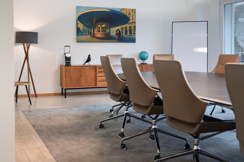 modern office meeting room with wooden desk, wooden chairs, beige carpet, painting, and wooden floor
