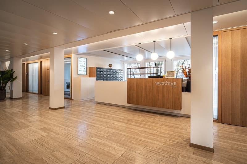 Open reception area, light wood flooring, warm ambient lighting, modern design, potted plant, wooden desk, glass walls