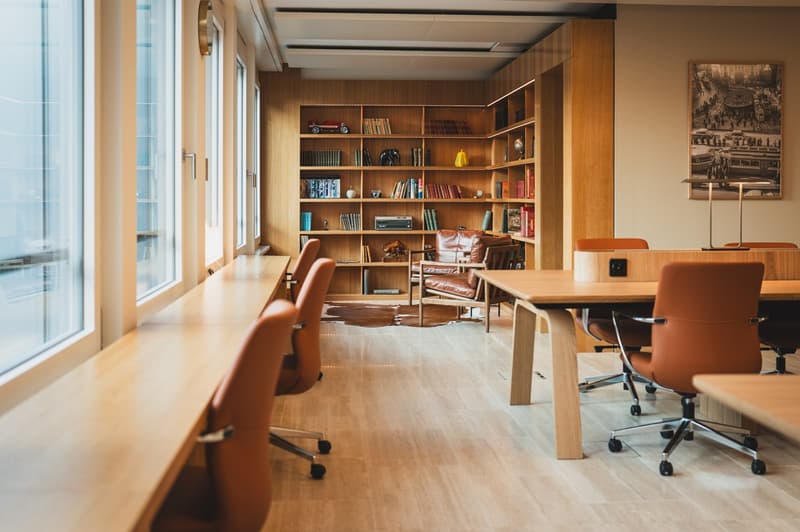 modern interior with wooden desks, chairs, bookshelves, glass windows, wooden flooring