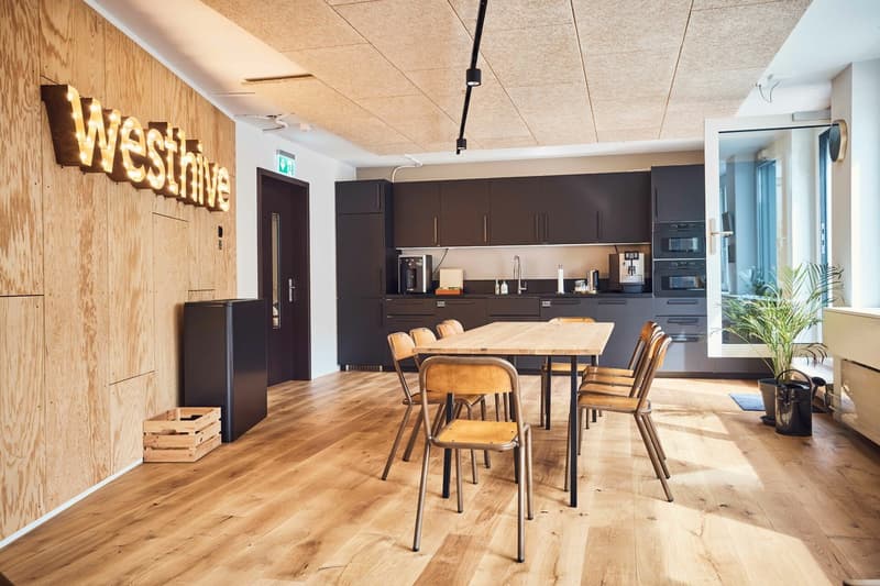 wooden cabinets, tiled floor, black table, chairs, kitchen appliances, wooden storage box, plant, wall with sign
