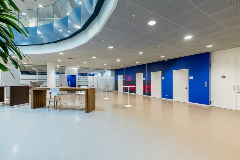 spacious office space, minimalist design, high ceilings, white walls, blue partitions, modern tables and chairs, glass railings