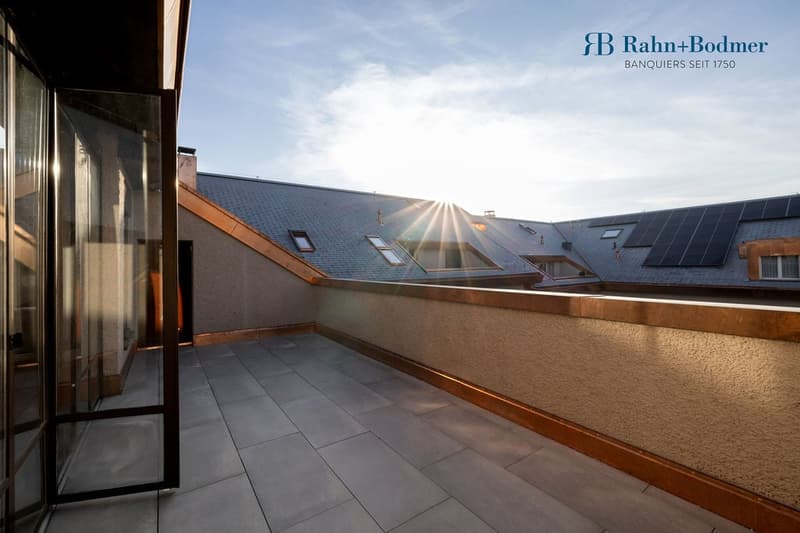 Rooftop terrace, tiled floor, sunlit, surrounded by stone wall, solar panels on neighboring roof