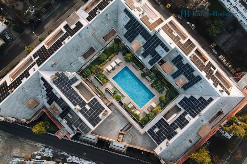 Solar panels, swimming pool in the center, modern architecture, multiple buildings