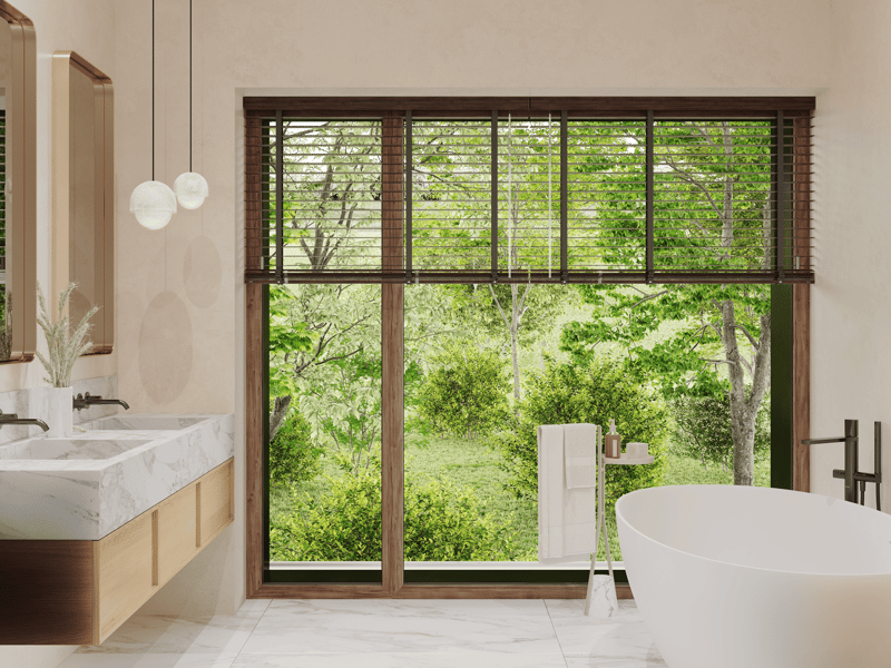 Double sink with modern faucets, walk-in shower, large bathtub, wooden frame, white marble flooring, pendant lights, large panoramic window, hanging towels, wooden cabinetry, potted plant, mirror