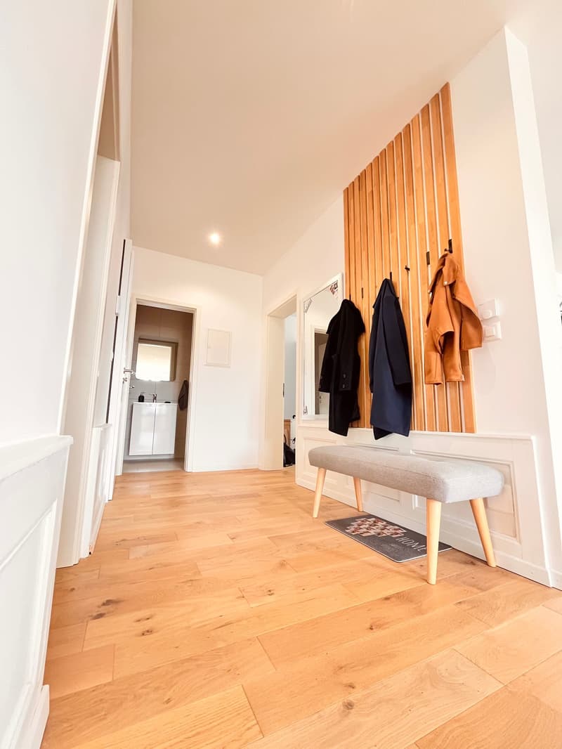 wooden floor, white walls, bench, coat hooks, mirror, sink